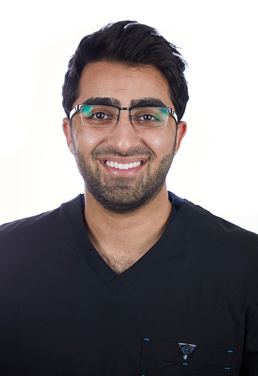 The Dentist UK team member Yahya in glasses and dark scrubs smiling for a headshot